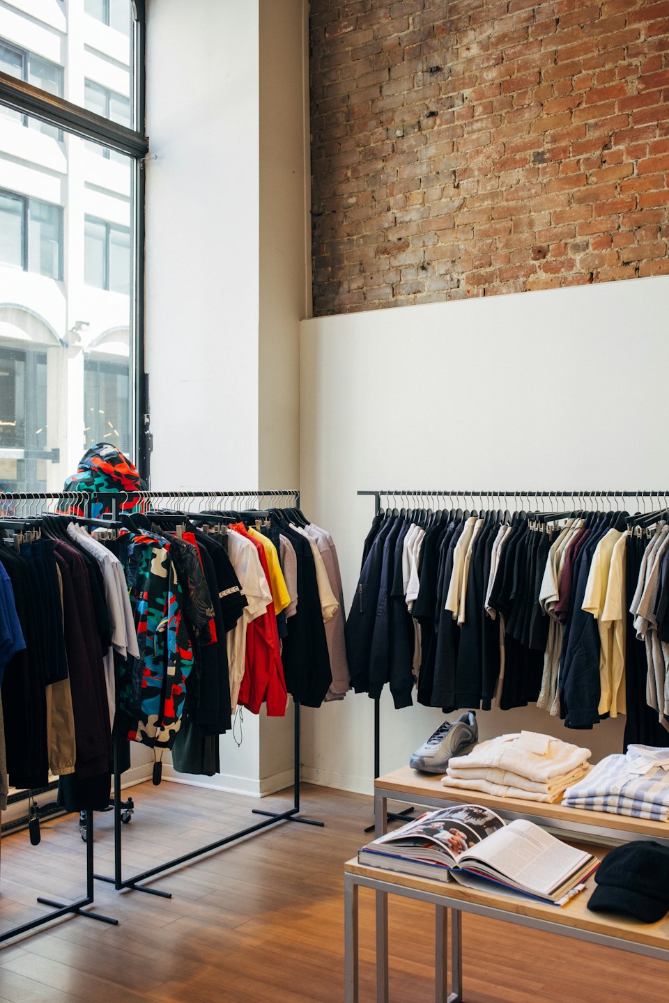 Abbigliamento in esposizione in una boutique con pareti di mattoni.