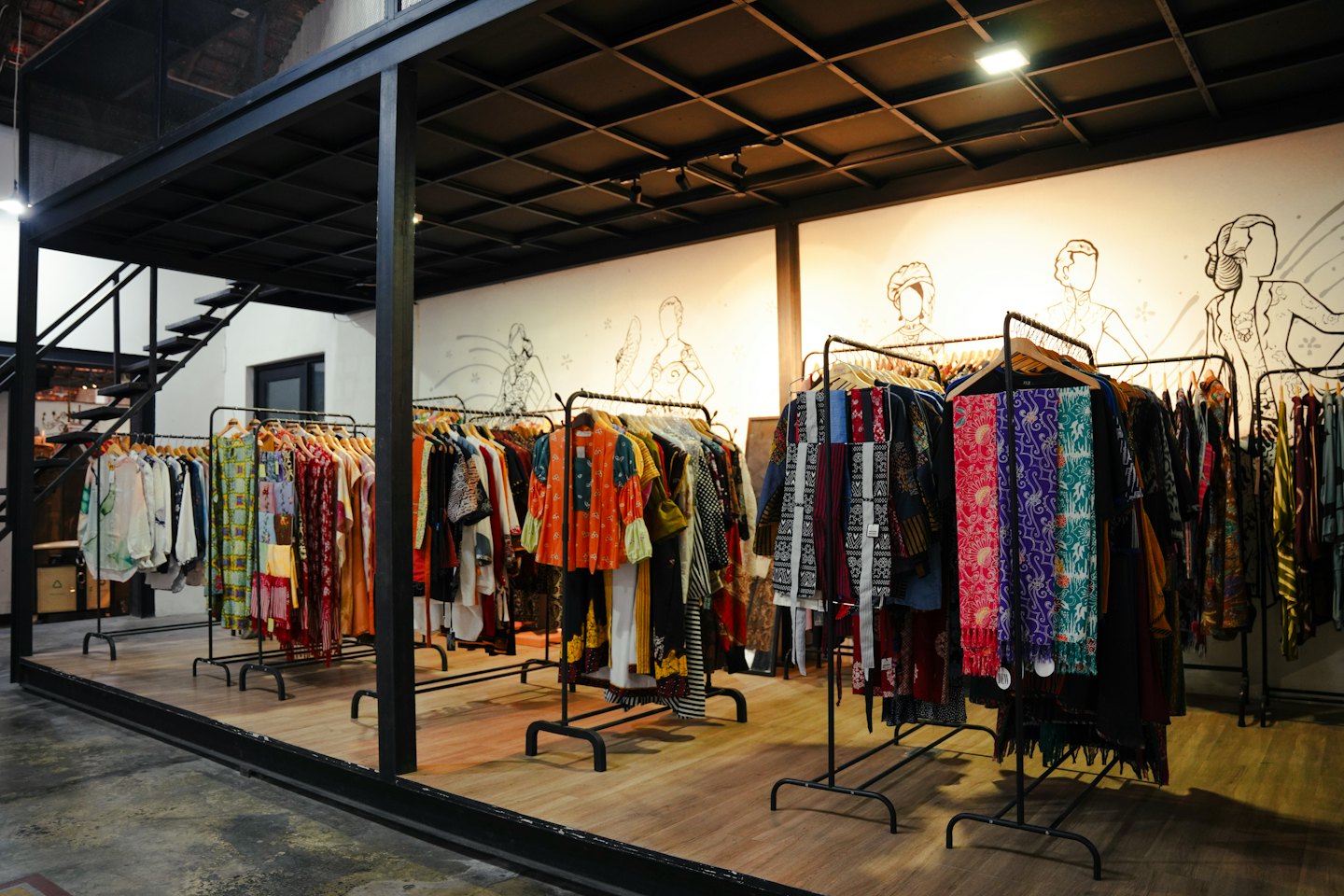Boutique di abbigliamento con scaffali di capi colorati e fantasia e struttura in stile industriale.